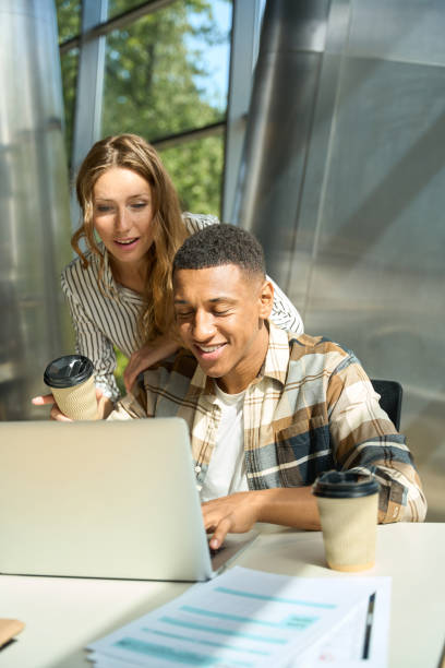 istock Smiling man and woman using laptop while looking at the screen 1454593119