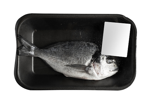 top view closeup one fresh sea bream in black transparent black vacuum packaging with blank white label isolated on background