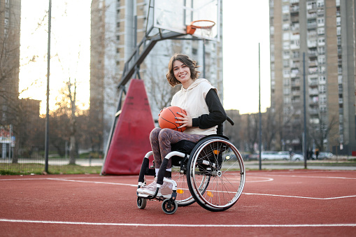 Disabled young woman playing basketball. About 25 years old, Caucasian brunette.