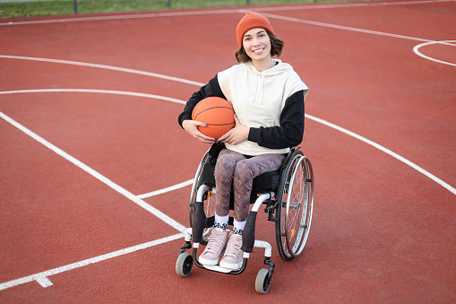 Disabled young woman playing basketball. About 25 years old, Caucasian brunette.