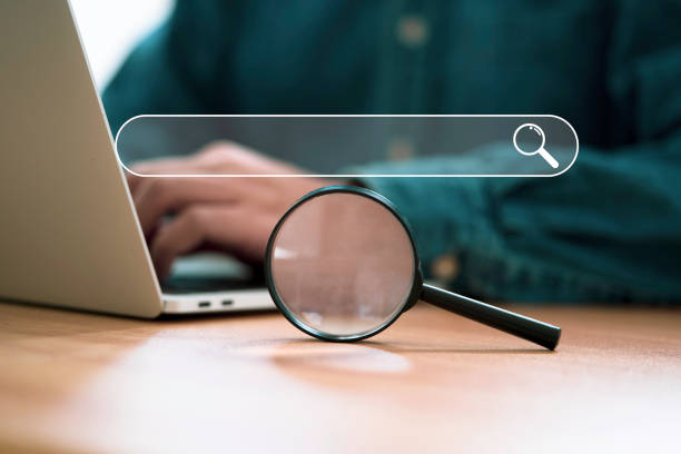 istock Businessman using computer laptop and magnifier glass with search icon for Search Engine Optimisation or SEO concept to find information by internet connection. 1454595933