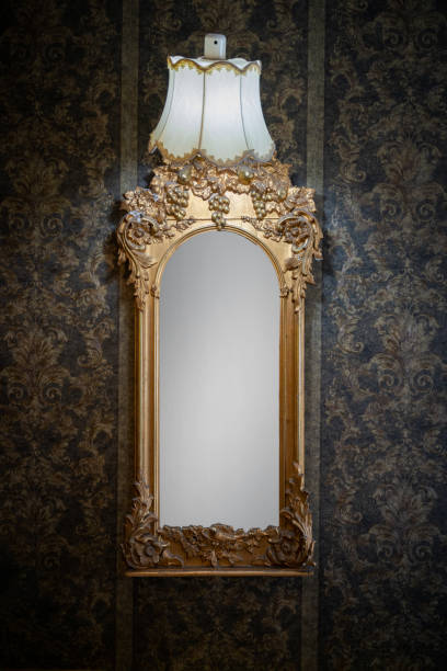 istock Vertical shot of an old, vintage mirror hanging on the black patterned wall 1454599121