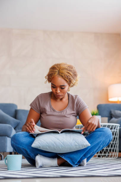 istock Woman reading a magazine while relaxing at home 1454604710