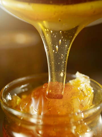Honey pouring into jar.