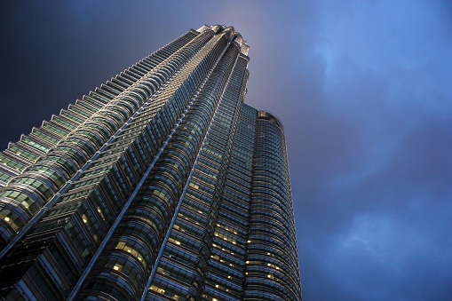 A low-angle view of glass-fronted buildings with business offices at night in Kuala Lumpur, Malaysia