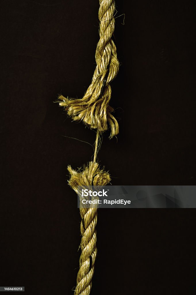 Fraying rope at breaking point, symbolizing danger and weakness Rope is down to its last strand, literally hanging by a thread. Bad Condition Stock Photo