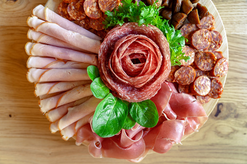 Top view of white bowl full of sliced prosciutto