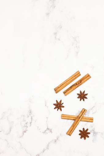 Cinnamon sticks and star anise on a marble kitchen counter in a top view