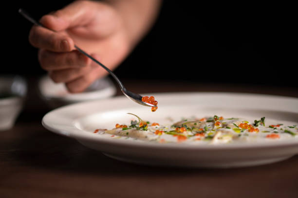 Chef putting caviar with a spoon on lasagna stock photo