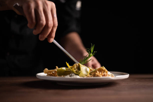 istock A male chef decorating a plate of artichoke 1454623647