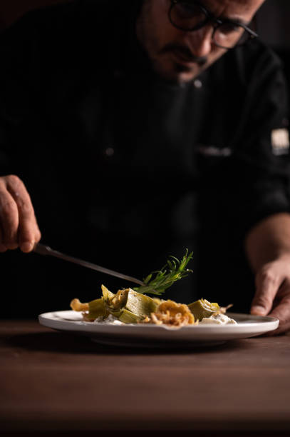 istock A male chef decorating a plate of artichoke 1454623704