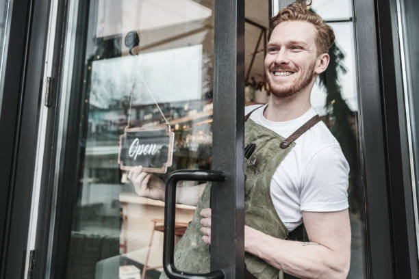 istock Young redhead barman opening the bar 1454623812