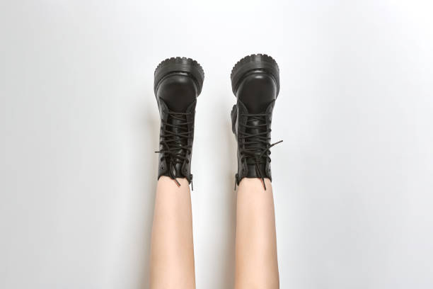 istock Woman legs in black combat boots on high heel platform with lug soles upside down, white background 1454624441