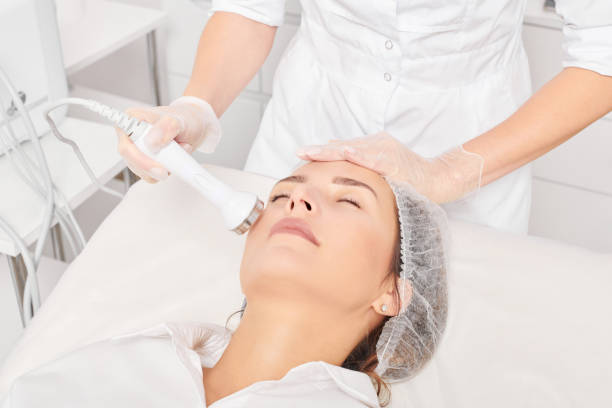 l’esthéticienne fait un resserrement de la peau par ultrasons pour le rajeunissement du visage de la femme en utilisant la phonophorèse - resserrer photos et images de collection