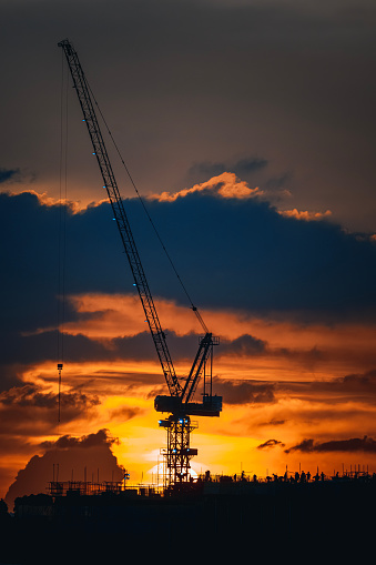 Sunset with silhouette crane on top of buildings
