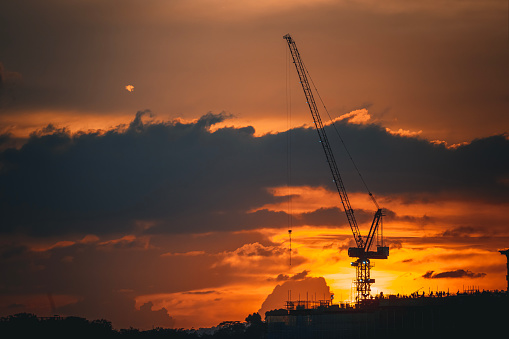 Sunset with silhouette crane on top of buildings