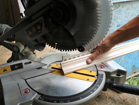 marking and cutting wooden planks on a miter saw, an angle saw in a carpenter's workshop while working with wood panels, trimming the ends of floor skirting boards on a miter saw
