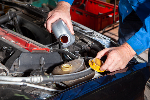 Auto repair shop - mechanic refills radiator anti-freeze