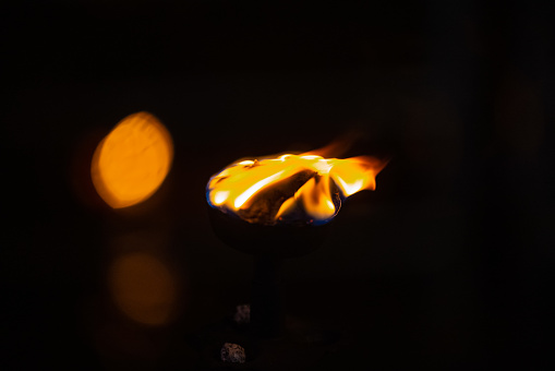 Fire flame at night with dark background during the ganga aarti rituals at river bank.