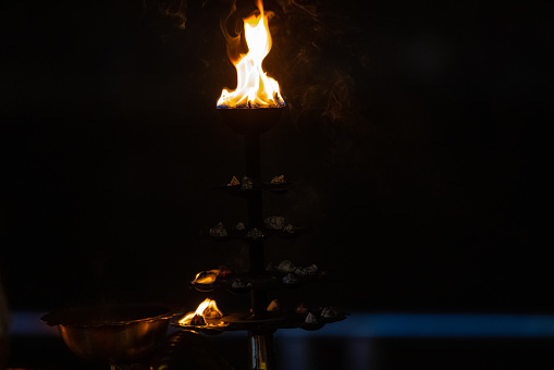 Fire flame at night with dark background during the ganga aarti rituals at river bank.