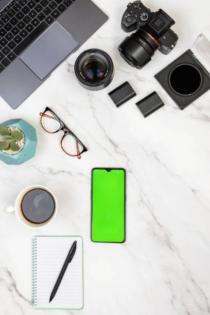 istock Modern white marble photographer workspace with laptop, camera, notepad, hot cup of coffee and mobile with green screen for chroma key. 1454632501