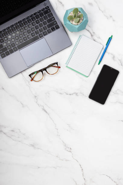 istock Modern desktop office top view of marble table with laptop, mobile, notepad and eyeglasses. 1454633719
