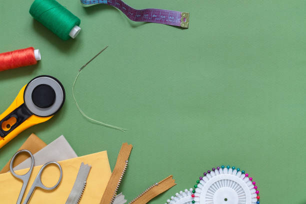 istock Sewing accessories on a green background. Rotary knife, fabric, scissors, zipper, pins, needle, threads spool. 1454637444