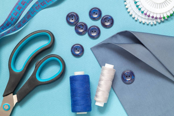 istock Sewing tools for tailoring on a blue background. Fabric, scissors, buttons, centimeter, pins, needle, threads spool. 1454637690