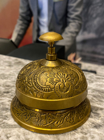 Stock photo showing close-up view of call bell sat on marble topped reception desk of a hotel.  These types of service bells are also known as a reception bell or concierge bell.