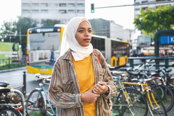 giovane donna con l'hijab sulla strada a berlino davanti all'autobus giallo - transportation bus mode of transport public transportation foto e immagini stock