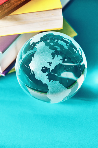 Glass sphere with world map etched on it, alongside a group of textbooks.