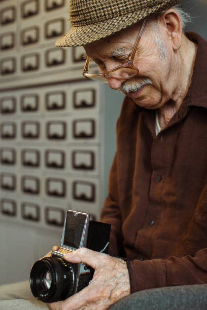 An old photographer with a medium format film camera in his hands. An old photographer with a medium format film camera in his hands. photographic film camera stock pictures, royalty-free photos & images