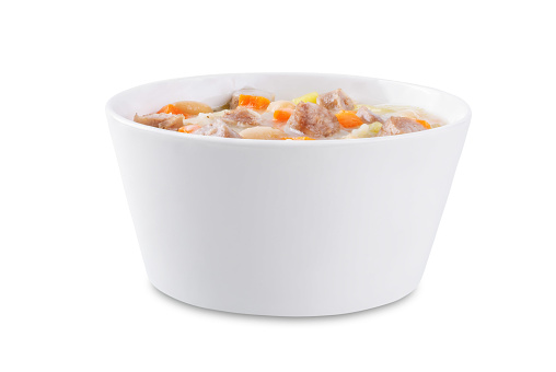 Potato carrot white bean soup with meat sausages in a bowl on a white isolated background. toning