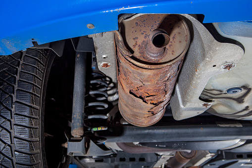 Auto repair shop, mechanic examines a rusted exhaust pipe