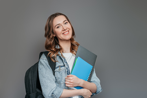 caucasian student girl over grey background looking away. copy space