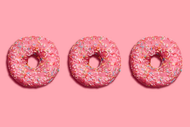 istock Donuts decorated icing and sprinkles on pink background. Top view photo. 1454652534