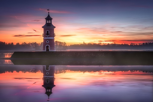 The reflection of Leuchtturm historical landmark and cultural property in Moritzburg, Germany at sunset