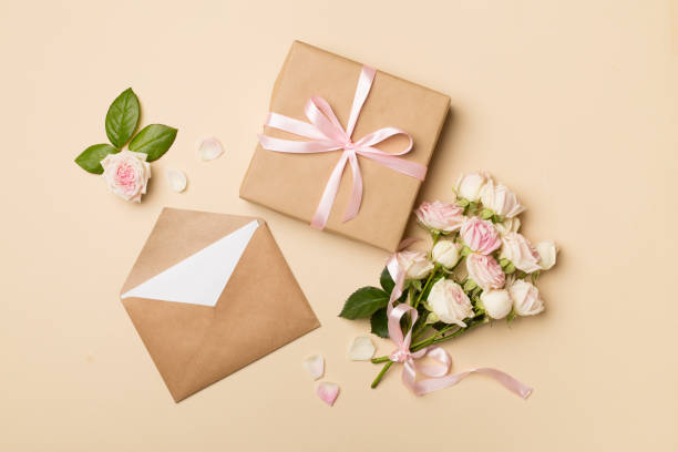 istock Envelope, gift box and rose flowers on color background, top view 1454657544