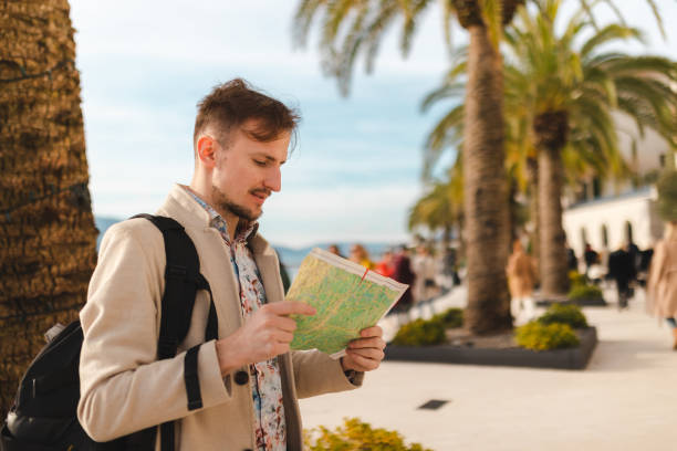 istock Handsome young male tourist looking at the map while on a vacation holiday 1454660026
