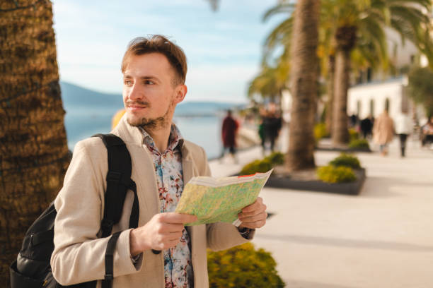 istock Lost young tourist looking at the map while on a summer vacation 1454660046