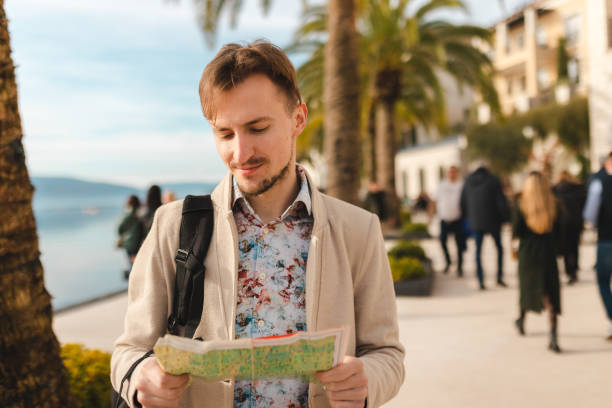 istock Handsome young tourist holding a map while wearing a backpack in a city 1454660063