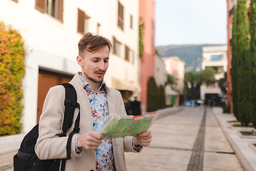 Waist up portrait of a male tourist holding a map. He is on vacation.
