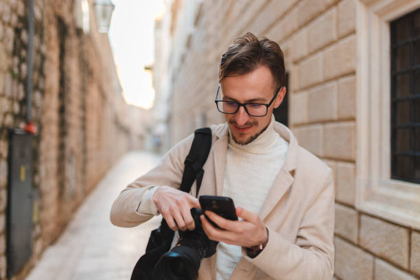 istock Handsome young man using his phone while on vacation visiting an old town 1454661355