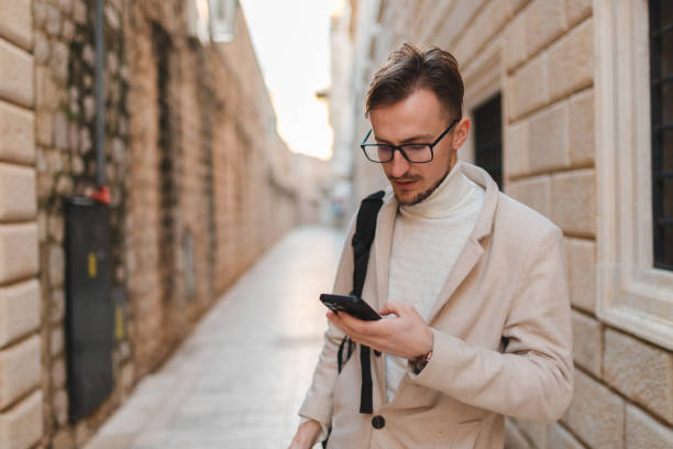 istock Handsome young man using his phone while on vacation visiting an old town 1454661357
