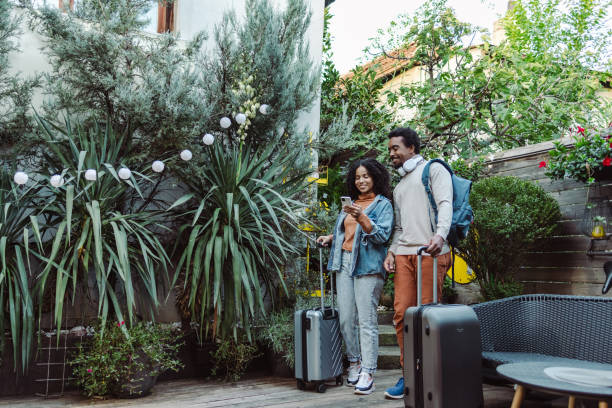 istock Young tourists with suitcases using smart phone 1454662030