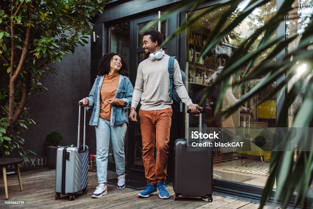 African-American tourists with suitcases in front of the rented apartment Happy young couple of African-American tourists with suitcases Travel Stock Photo