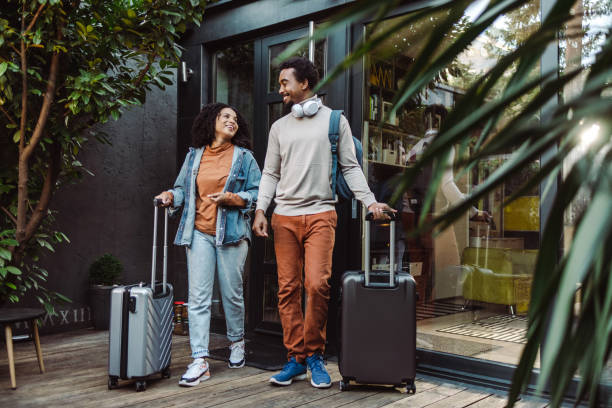 African-American tourists with suitcases in front of the rented apartment Happy young couple of African-American tourists with suitcases building entrance photos stock pictures, royalty-free photos & images