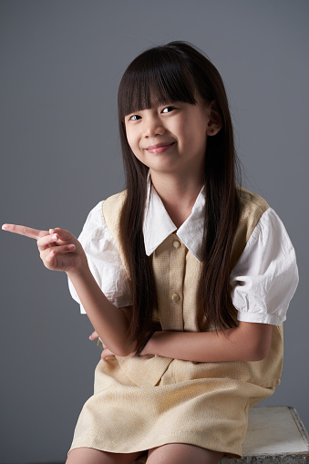 chinese little girl sitting with hand pointing a direction