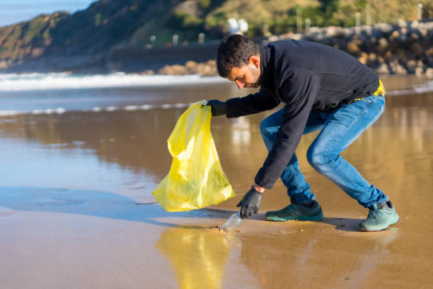 istock Volunteer man collecting garbage or plastic on the beach. ecology concept 1454664528