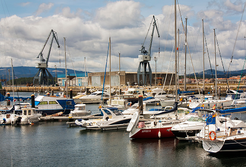 Rows of sailboats and fishing boats, masts , pier, commercial dock, harbor cranes in the background. Marina in Vilagarcía de Arousa, O Salnés, Rías Baixas, Pontevedra province, Galicia, Spain.